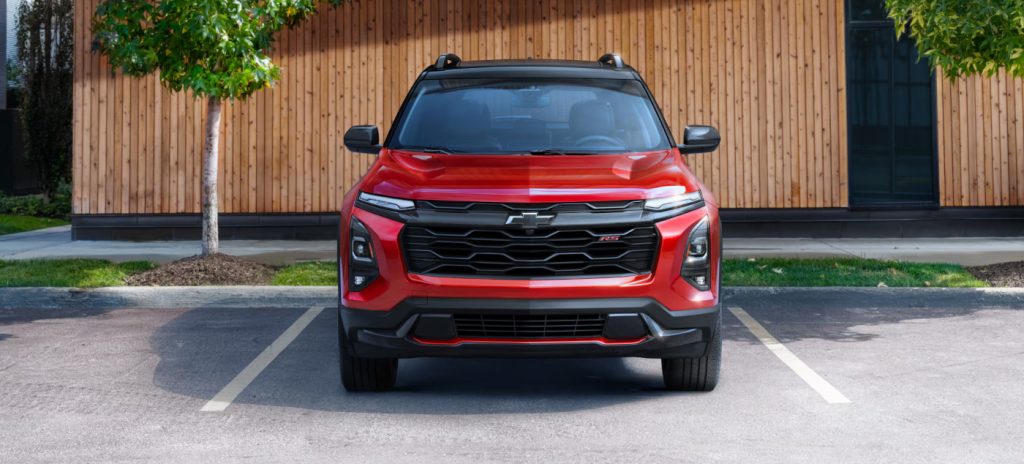 Image of the front view of a red 2025 Chevrolet Equinox in a parking lot with trees
