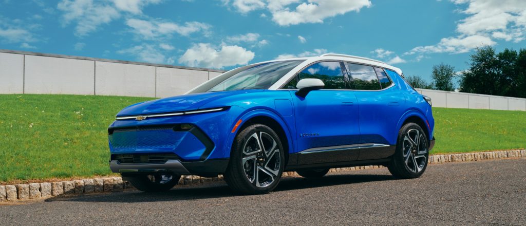 Image of a blue 2025 Chevrolet Equinox EV driving on a road.