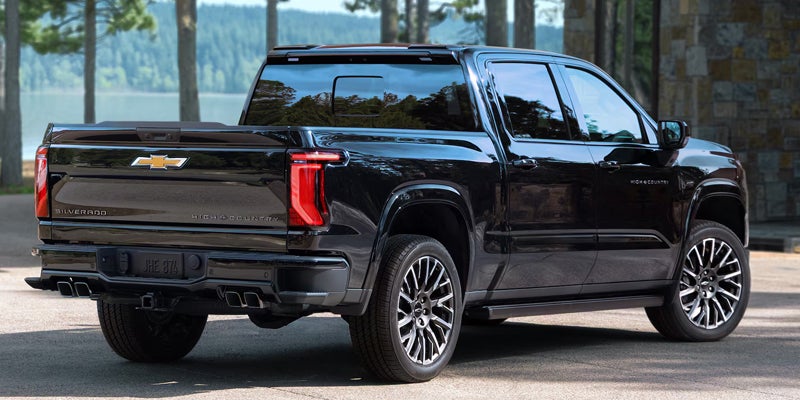 Rear view of a black 2027 Chevy Silverado 1500 parked near a lake