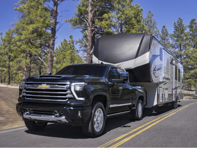 New black Chevrolet Silverado 2500 HD towing a large camper
