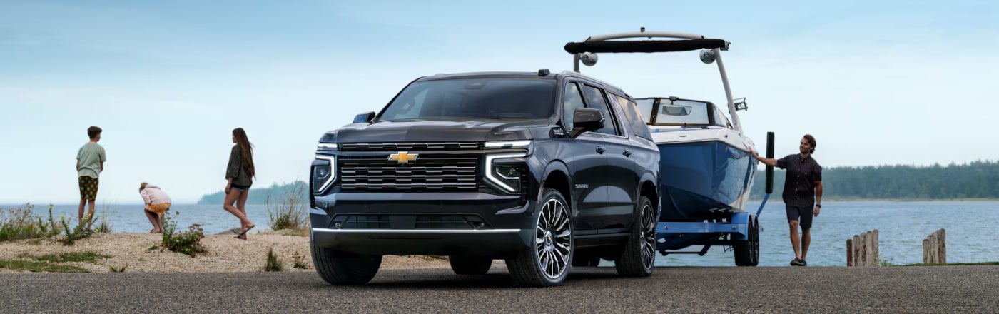 image of a family with a black Chevrolet Suburban towing a boat in front of a lake